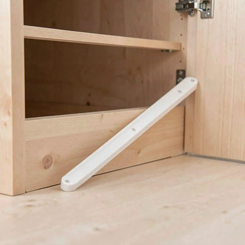 Close-up of a white plastic drawer slide installed in a kitchen cabinet for smooth operation, featuring precision groove tracks.