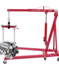 Hoss Strength Folding Engine Hoist With Lever 2 Ton Hydraulic Cherry Picker lifting an engine, heavy duty steel frame, six smooth rolling casters.