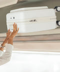 Person storing 18 Inch Underseat Carry On Luggage With Wheels Lightweight Hard Shell Suitcase in overhead compartment on plane.
