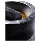 Close-up of Granite Mortar And Pestle Set With Gold Base, 2 Cup Capacity, showing grinding spices inside the bowl.