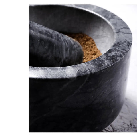 Close-up of Granite Mortar And Pestle Set With Gold Base, 2 Cup Capacity, showing grinding spices inside the bowl.