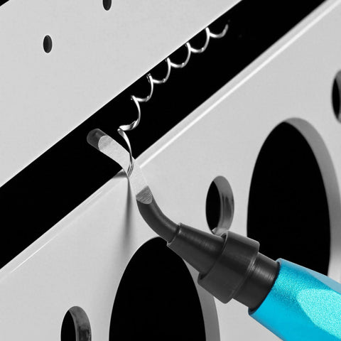 Close-up of a blue-handled deburring tool with curved swivel blade removing burr from metal edge.