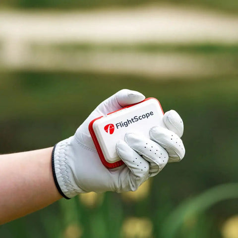 Golfer holding Mevo Portable Golf Launch Monitor And Rangefinder With Signature Gift Bundle in hand outdoors.
