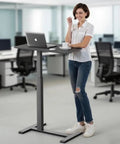 Person using Mobile Standing Desk With Wheels Height Adjustable Pneumatic Laptop Desk in office setting
