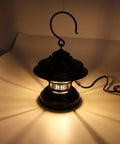 Retro LED Camping Lantern Portable Hanging Light With Dual Power Supply IPX4 Waterproof, illuminating on a tabletop.