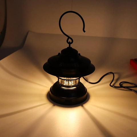 Retro LED Camping Lantern Portable Hanging Light With Dual Power Supply IPX4 Waterproof, illuminating on a tabletop.
