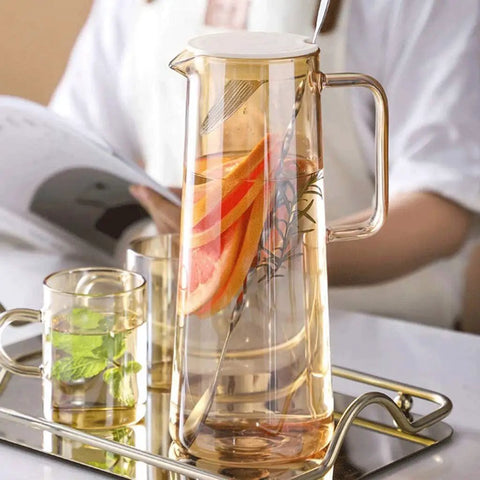 A Game Changer High Borosilicate Glass Pitcher With Secure Tight Lid And Long Mixing Spoon One Point Six Liter Heat Resistant Beverage Carafe pouring iced tea with lemon.