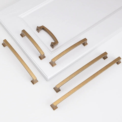Hella Durable Five Inch Antique Brass Cabinet Pulls And Drawer Handles With Smooth Satin Finish, displayed on a white surface.