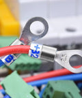 Electrical cables with metal ring terminals connected to labeled equipment, showing a close-up of wire organization.