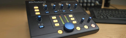 Beast Pro Desktop Studio Control Hub With Four Stereo Input Pairs And SPDIF Digital Input on wood desk next to keyboard.
