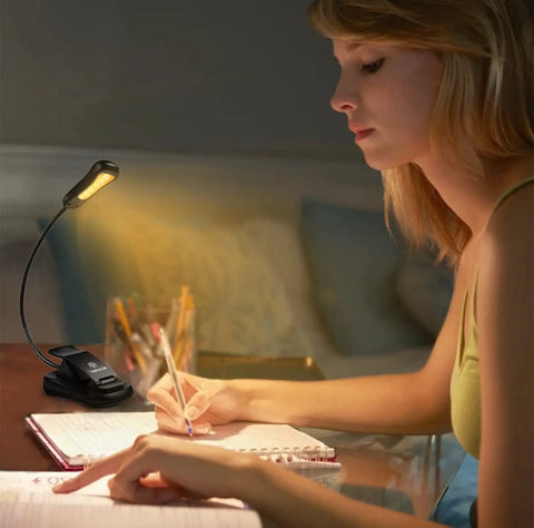 Woman using Clip-On Reading Light for Books in Bed, Car and Travel, 3000K Warm LED, Rechargeable and Eye Friendly, writing in notebook