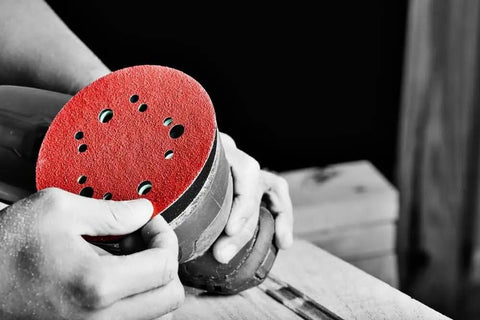 Hook And Lock ROS Sanding Discs For Wood Metal And Plastics 5 Inch 120 Grit held by a person on a sander.