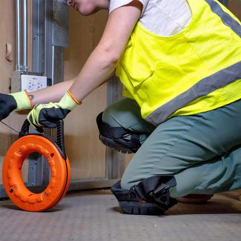 Worker wearing lightweight gel knee pads with slip resistant caps and adjustable straps on construction site for ergonomic comfort.