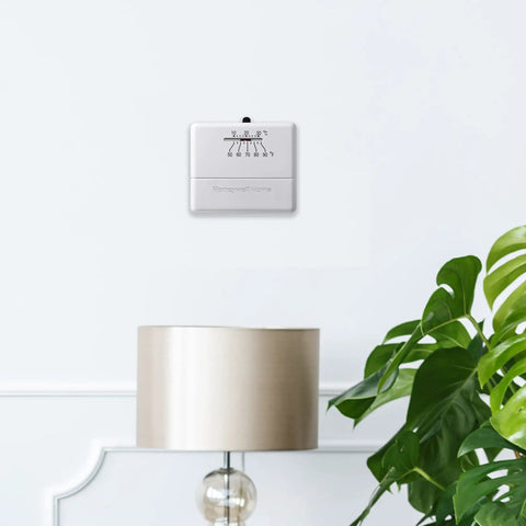 Wall-mounted Economy Millivolt Non Programmable Thermostat White With Simple Temperature Control above a lamp and plant