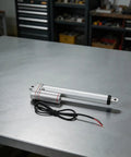 12V Electric Linear Actuator With Straight Push Pull Rod For Heavy Duty Industrial Automation And Sofa Lifts IP65 Waterproof on a steel surface.