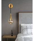Slick Premium Copper LED Wall Sconce Featuring Glare Free Crystal Shade For Modern Bedroom Bedside Hallway And Staircase Decor With Tight Rust Proof Build And Killer Warm Ambient Glow mounted beside bed.