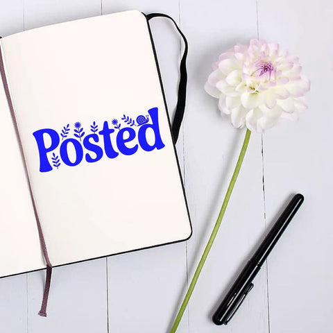 Floral 'Posted' imprint from Go To Small Duo Hand Stamp on open notebook, flower and pen nearby.