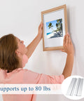 Woman hanging a picture frame using the 12 Pack French Cleat Wall Mount Brackets With Z Bar Supports And Silicone Dots Heavy Duty Killer Grip Picture Hanger Kit For Headboard Mirror Whiteboard No Sweat Setup 12 Inch.