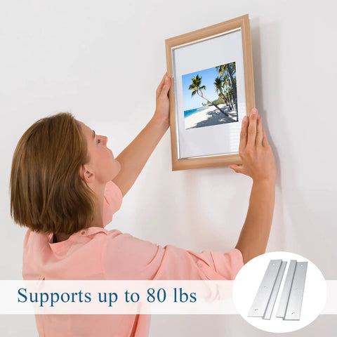 Woman hanging a picture frame using the 12 Pack French Cleat Wall Mount Brackets With Z Bar Supports And Silicone Dots Heavy Duty Killer Grip Picture Hanger Kit For Headboard Mirror Whiteboard No Sweat Setup 12 Inch.