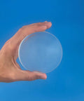 Large Clear Gel Furniture Pads For Hardwood Floors That Kick Scratches To The Curb With Squishy Shock Absorbing Grips For Slippery Floors In A Nearly Invisible Pack Of Twelve Smooth Ride Surface Protectors held in hand against blue background.