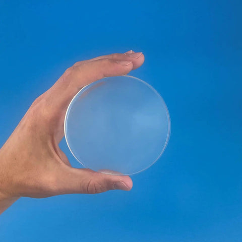 Large Clear Gel Furniture Pads For Hardwood Floors That Kick Scratches To The Curb With Squishy Shock Absorbing Grips For Slippery Floors In A Nearly Invisible Pack Of Twelve Smooth Ride Surface Protectors held in hand against blue background.