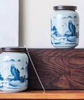 Top Shelf Airtight Ceramic Tea Canister Keeping Freshness Locked Inside Retro Blue And White Landscape Vibes, two jars displayed on wooden surface.