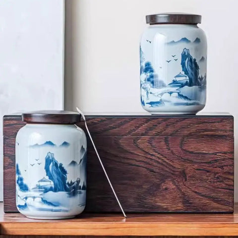 Top Shelf Airtight Ceramic Tea Canister Keeping Freshness Locked Inside Retro Blue And White Landscape Vibes, two jars displayed on wooden surface.