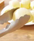 Close-up of brushed black 9-inch stainless steel tong gripping food, showing ergonomic grip and locking mechanism.