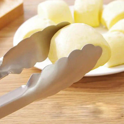Close-up of brushed black 9-inch stainless steel tong gripping food, showing ergonomic grip and locking mechanism.
