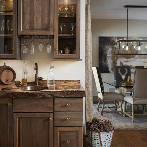 Kitchen with wooden cabinets and countertop, featuring antique brass cabinet knobs, glassware, and decorative items.
