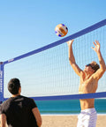 People playing on beach with Heavy Duty Outdoor Volleyball Net Set With Anti Sag Design And Adjustable Aluminum Poles Portable Backyard Beach Net System Blue For Grass And Sand Easy Setup And Sturdy Stands For Competitive Play.