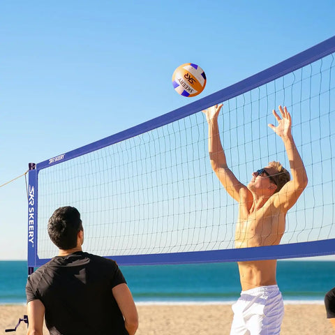 People playing on beach with Heavy Duty Outdoor Volleyball Net Set With Anti Sag Design And Adjustable Aluminum Poles Portable Backyard Beach Net System Blue For Grass And Sand Easy Setup And Sturdy Stands For Competitive Play.