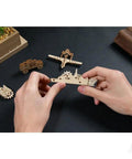 U Fidgets Invincibility Dope DIY Gear Spinner Fidget Toy With Tiny Hanging Eyelet That Doubles As Ornament Or Keychain, Made From Natural Composite Wood You Can Leave Bare Or Color With Paint Or Stain. Wooden ship model held in hands on black desk