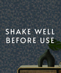 Blue patterned wallpaper with 'Shake Well Before Use' text, vase and books, relates to EZ Hang Peel And Stick Wallpaper Helper Clear Spray.
