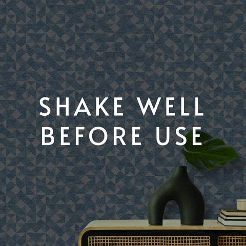 Blue patterned wallpaper with 'Shake Well Before Use' text, vase and books, relates to EZ Hang Peel And Stick Wallpaper Helper Clear Spray.