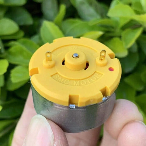 Close-up of a Two Pack RC500 KN Mini 32mm Round Spindle Motor DC 6V 12V 5300 RPM High Torque Carbon Brush held in hand outdoors