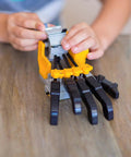 Hands On Motorized Robot Hand Kit For Kids A Fun Do It Yourself STEM Toy That Lets You Build A Working Robotic Hand Controlled By A Programmable Drum With Peg Based Patterns And Endless Rhythm Experiments. child assembling robot hand kit