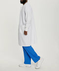 Side view of Relaxed Fit Unisex Full-Length Lab Coat With Snap Front And Two Spacious Pockets, model wearing blue pants