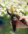 Heavy Duty Pruning Shears For Garden Work With Foam Grip Handles, Bypass Hand Pruners And Eight Inch Garden Clippers For Plant Cutting And Hedge Trimming, Pro Grade Stainless Steel Blades Cut Up To Three Quarters Of An Inch being used to trim a branch with white flowers.