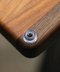 Close-up of Badass Non Slip Cutting Board Feet with clear rubber bumper pad and heavy stainless steel screw on wood surface.