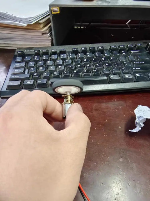 Hand holding 12V DC Mini Gear Motor N20 with D Shaft, fixed frame, mount nut, and plastic wheel for DIY science projects.