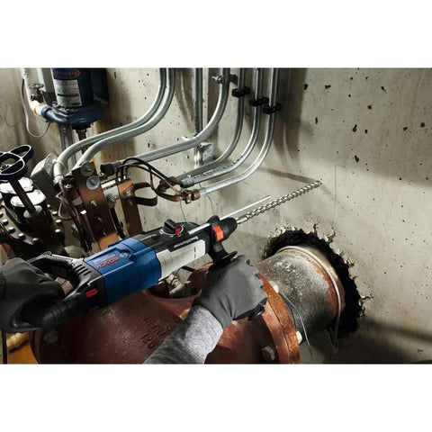Worker using Beast Half Inch By Ten Inch By Twelve Inch SDS-Plus Bulldog Xtreme Carbide Rotary Hammer Drill Bit on concrete wall.