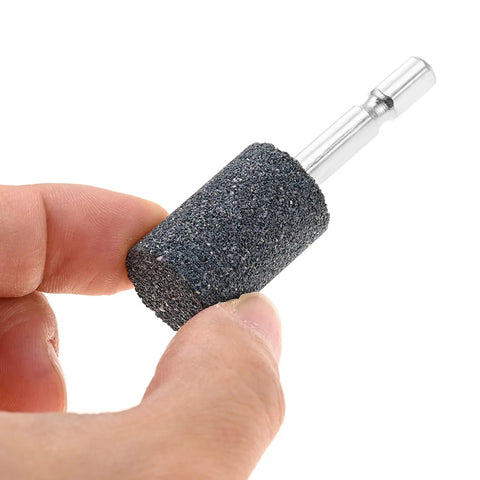 Hand holding a 20mm aluminum oxide cylindrical grinding stone with 1/4 inch hex shank from a Ten Piece 20mm Aluminum Oxide Cylindrical Mounted Grinding Stones Set With One Quarter Inch Hex Shank For Electric Rotary Tools Drill Grinder Pro Grade Durable For Metal Shaping Deburring And Precision Work