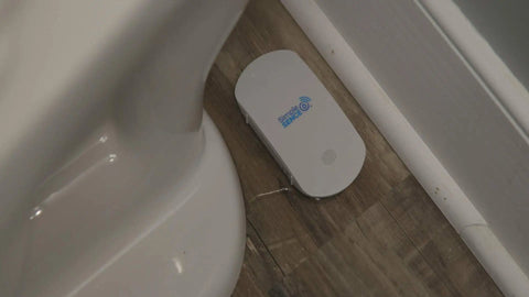 Smart WiFi Water And Freeze Detector With 80dB Audible Alarm Text And Email Alerts Continuous Home And Investment Property Monitoring Two Year Battery Life With Replaceable AAA Batteries on bathroom floor.