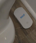 Smart Water Leak And Freeze Detector With WiFi Alerts, 80dB Audible Alarm, shown next to a toilet on wooden floor.