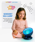 Girl sitting beside Calming Autism Sensory Sea Lamp Night Light Projector, showing blue light mode and packaging.