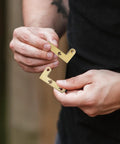 Hands holding two gold 360 Degree Rotating Pivot Hinge Set For Concealed And Secret Doors with mounting holes.