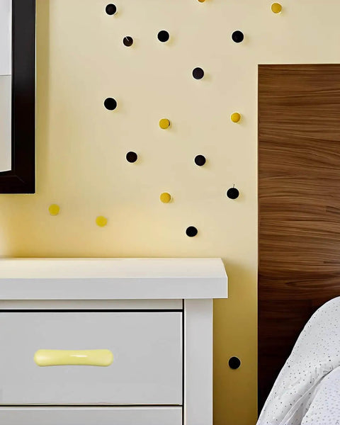 Four Piece Set Of Glossy Yellow Ceramic Cabinet Pulls Featuring A Slick High Gloss Finish And Heavy Duty Craftsmanship Ideal For Kitchen Cabinets And Zero Sweat Home Renos on white drawer against yellow wall with decorative dots.