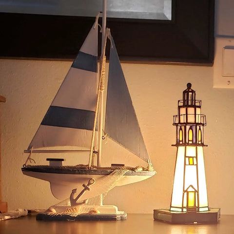 Lighthouse Style 10 Inch Tiffany Glass Table Lamp Handcrafted Stained Glass Accent Light illumination next to a sailboat model.