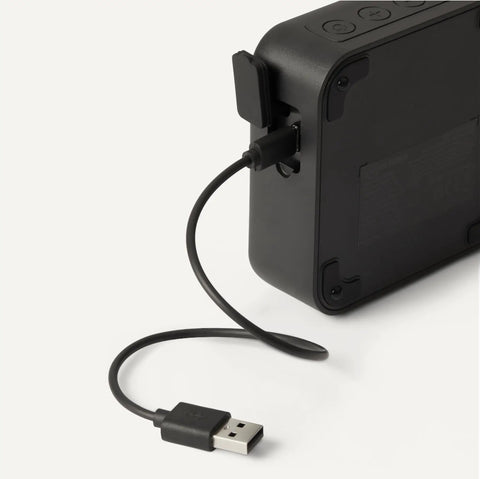 Back view of Compact Bluetooth Speaker With IPX5 Waterproof Rating, 6 Hour Playtime, USB C Charging cable shown connected